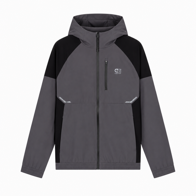 A colorblock hooded jacket in dark gray and black, featuring a full-zip front, a small white logo on the left chest, and reflective silver details on the front pockets, shown against a plain white background.