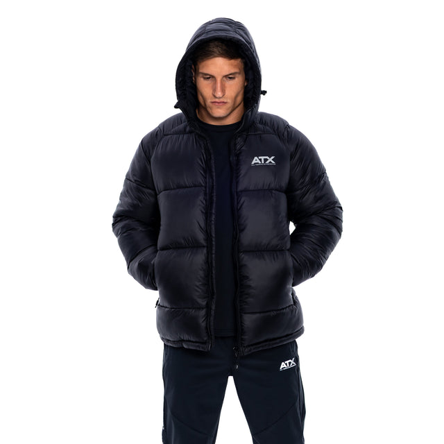 A man wearing a black puffer jacket with a white ATX logo on the chest, paired with matching black pants, shot against a solid white background.