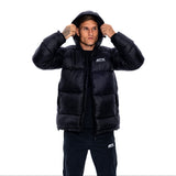 A man wearing a black puffer jacket with a white ATX logo on the chest, posing with the hood up against a solid white background.
